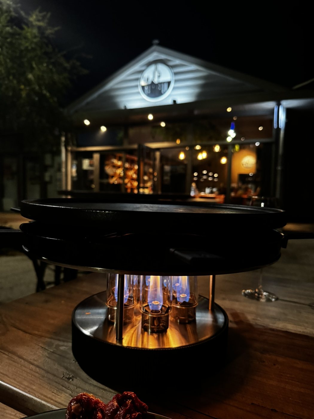 Grill de table allumé en terrasse le soir devant la façade du Nabu