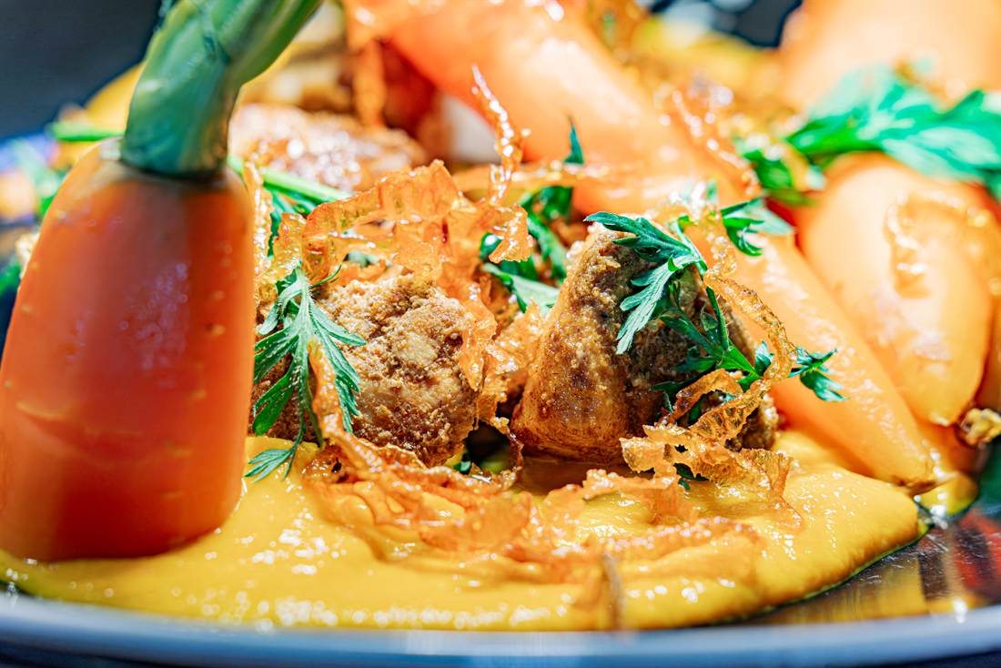 Plat du jour en gros plan, légumes glacés et jus corsé